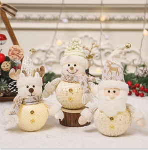Detailopname van gebreide kerstpoppen met gouden lovertjes en bellenmutsen op een sfeervolle plek