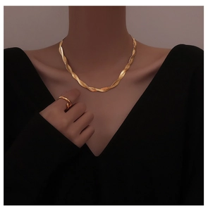 Detail of twisted gold layered necklace and open ring set on model with black outfit