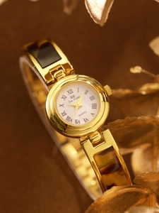 Detail of tortoise shell link bracelet and gold quartz watch with Roman numerals