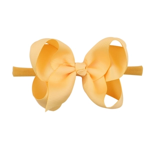 Detailed close-up of a large pale orange ribbed bow on a soft nylon elastic headband