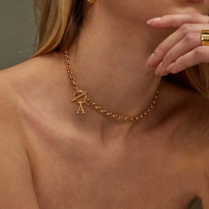 Close-up of a gold letter A pendant necklace featuring a toggle clasp and round link chain