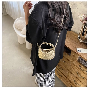 Mini gold quilted crossbody bag with metal chain shown on shoulder for size perspective