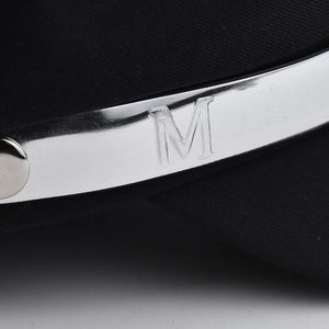 Classic black newsboy hat with a silver metal trim featuring an engraved letter M detail