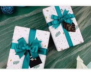 Detail of white wrapping paper with geometric leaf patterns and dark green satin ribbons