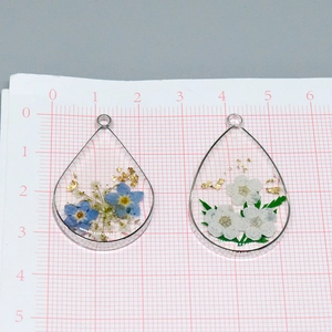 Detailed view of teardrop resin pendants with dried daisy flowers and gold foil accents