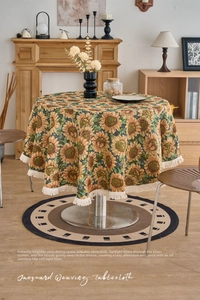 Detailed close-up of sunflower jacquard weaving texture and white fringe on round tablecloth