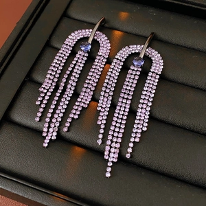 Close-up of U-shaped tassel earrings with purple and blue crystals on black leather