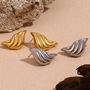 Detail of gold and silver liquid waterdrop earrings on stone and wood aesthetic background