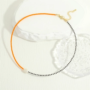 Detail of bohemian necklace with orange glass beads and a white freshwater pearl pendant