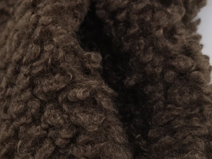 Close-up of deep brown curly faux shearling fabric with soft dense texture detail