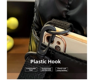 Detail of plastic swivel hook and woven strap on a black quilted puffer bag with a phone