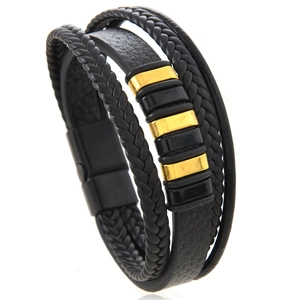 Détail d'un bracelet multicouche en cuir tressé noir avec perles dorées et fermoir magnétique