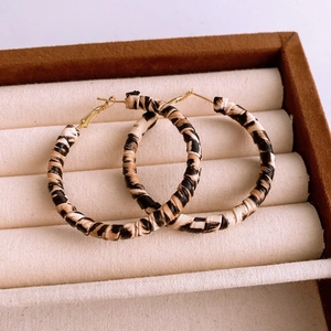 Detail shot of leopard print wrapped hoop earrings in a beige velvet jewelry organizer