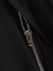 Dettaglio macro della cerniera in metallo argento sui pantaloni larghi neri