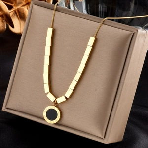 Macro detail of gold necklace with Roman numeral black pendant on jewelry display box