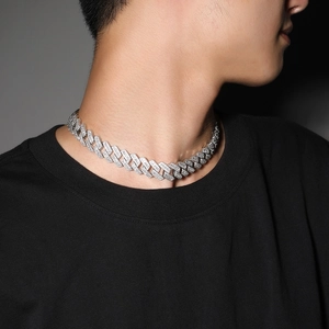 Macro view of silver cuban link chain with zircon stones worn by a model on a dark background