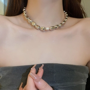 Detailed view of an irregular silver bead necklace with a central pearl on a model