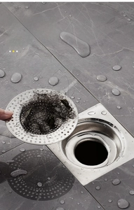 Close-up of stainless steel drain strainer with fine holes on marble floor