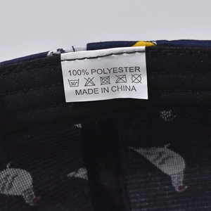 Detail view of internal wash label on navy blue polyester baseball cap showing material info