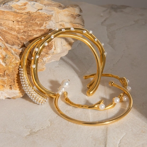 Polished gold open bangles with white pearls and zirconia accents on stone base