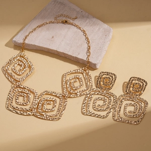 Detaillierte Nahaufnahme des goldfarbenen Schmucksets mit gehämmerten quadratischen Spiralen