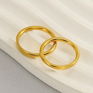 Two minimalist 18k gold plated stainless steel rings displayed on a white wavy tray