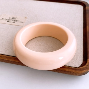 Détail d'un large bracelet jonc en résine acrylique crème avec une finition polie
