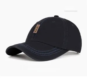 Close-up of navy blue washed baseball cap with brown leather patch and metal rivets detail