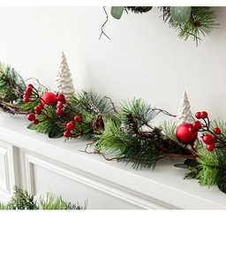 Detailed Christmas garland with red berries and pine needles on a white fireplace mantel