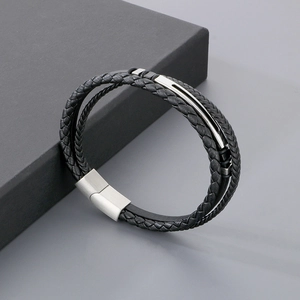 Detail of multi-layer black braided leather bracelet with silver metal plate on gift box