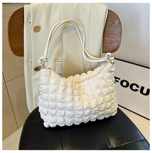 Detailed macro shot of white popcorn textured fabric and dual straps on cloud shoulder bag