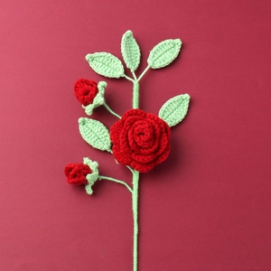 Rosa rossa fatta a mano all'uncinetto con boccioli e foglie verdi per decorazione casa