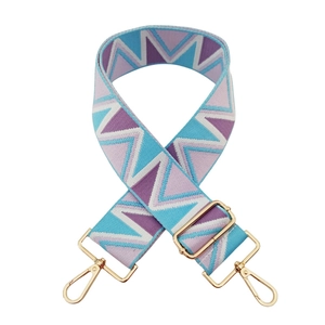 Detail of adjustable geometric jacquard bag strap with golden metal lobster clasps