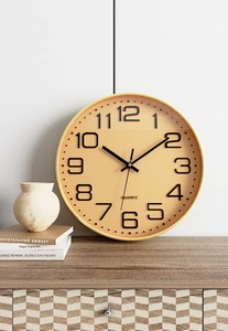 Detail of a minimalist 12-inch wall clock with a gold frame and champagne quartz dial