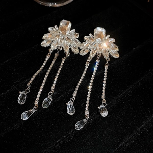 Detailed view of crystal flower tassel earrings with teardrop pendants on velvet tray