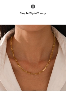 Close-up of a minimalist gold paperclip link necklace worn on a model with a white shirt