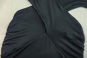 Detail of the black ruched bodycon dress showing the twist knot and fabric texture