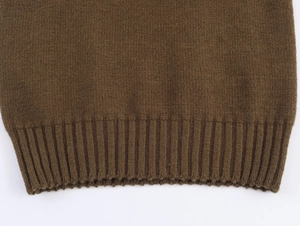 Détail macro du gilet en maille marron montrant l'ourlet côtelé et la texture tricotée