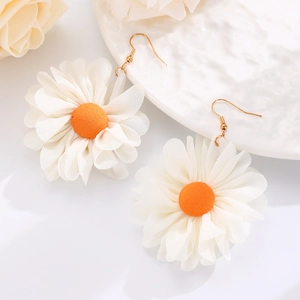 Macro detail of daisy flower drop earrings with white petals and gold-finished hooks