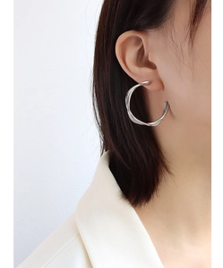 Close-up of silver twisted double-layer hoop earring worn by a model on plain background