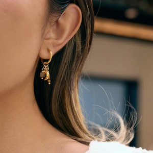 Boucles d'oreilles créoles dorées avec pierre oeil de tigre et lune sur mannequin