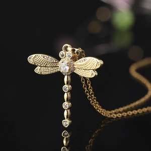 Macro shot of gold-plated dragonfly pendant with cubic zirconia wings and fine details