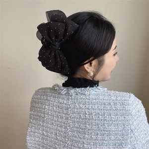 Elegant black polka dot mesh bow hair claw clip styled on a woman's bun hairstyle