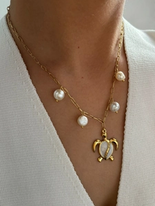 Detail of a gold turtle pendant with shell inlay and pearls on a dainty link chain