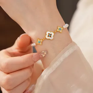 Elegante bracciale placcato oro 18k con perle e ciondoli a quadrifoglio sul polso