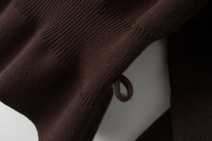 Detail of dark brown knit fabric with fine ribbed texture and matching hanging loop