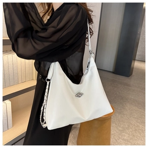 Detail of white shoulder bag featuring a unique planet-shaped metal rotating lock and chain strap