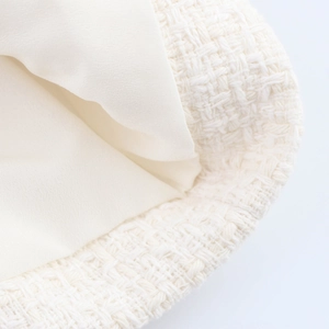 Close-up of white tweed fabric texture with smooth inner lining on a stylish garment