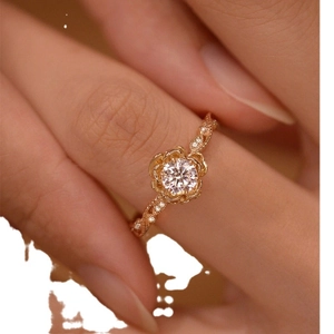 Elegant rose gold ring with flower-shaped setting and sparkling zircons on female hand