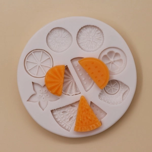 Makroaufnahme einer Silikonform mit Fruchtformen und kleinen orangefarbenen Abgüssen